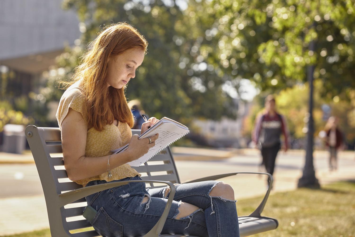 一位<a href='http://o72.lkmjfh.com'>bv伟德ios下载</a>学院的学生在校园里的长椅上读书.